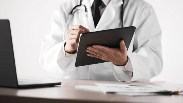 Hastane ofisindeki masada steteskoplu bir doktor. Sistematik sağlık yönetimi için bir doktora danışıyorum..