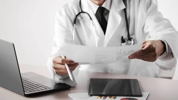 Hastane ofisindeki masada steteskoplu bir doktor. Sistematik sağlık yönetimi için bir doktora danışıyorum..