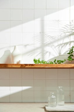 Duvarı ve beyaz fayansları olan beyaz ahşap bir raf. Sıcak güneş ışığı ve doğa tarafından kucaklanan huzurlu bir yer. Uyum, konfor ve zarif güzelliğin bir araya geldiği yer..