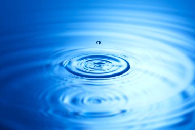 Mavi su yüzeyine düşen su damlası