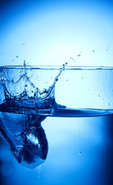 Su köpüklü mavi bardakta sıçrıyor.