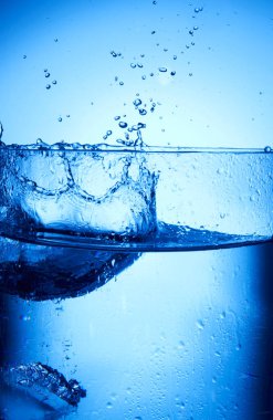 Su, mavi buz küpleriyle bardağa sıçrar.