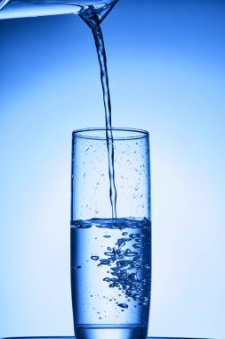 Mavi zemin üzerinde su bardağı olan su sıçraması..