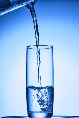 Su, mavi zemin üzerinde buzla bardağa sıçrar.