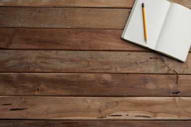 Boş defterin üst görüntüsü, tahta masadaki kalem..
