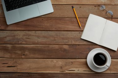 Kahvenin ve defterin ahşap masadaki üst görüntüsü.