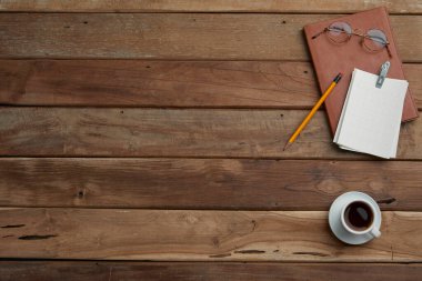 Tahta bir masanın üzerinde not defteri olan kahve fincanı.