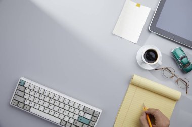 Gri arka planda bilgisayar, fare, kalem ve kahve ile işyerinin üst görünümü