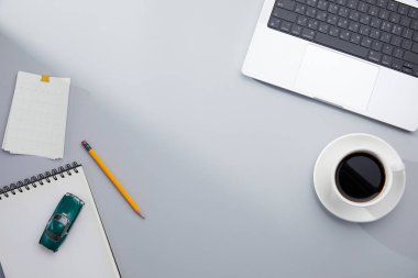 Dizüstü bilgisayarı, kahve fincanı, kırtasiye malzemesi ve diğer eşyalarla ofis masaüstü görüntüsü. 