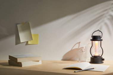 Lamba, kitap ve lamba. Odadaki ahşap masada bir mum.