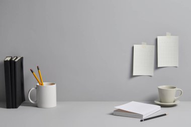 Beyaz arka planda afiş, not defteri, kahve, kalem ve bir fincan çay.