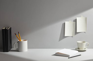 Boş siyah kitap ve kalem beyaz boş sayfalar, bir fincan kahve, lamba ve ahşap bir masada kırtasiye..