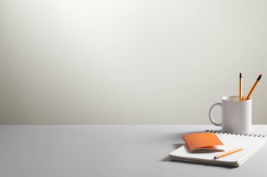 Boş kalem, kahve fincanı, kalem, kalem, kağıt kalem ve kalem içeren boş bir defter..