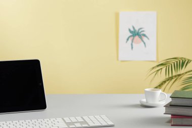 Bilgisayar, kitap, defter ve kaktüs renkli duvarın yanındaki masada. Ev içi ofis içi. metin için boşluk kopyala.