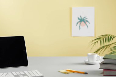 Bilgisayar, kitaplarla ve bitkilerle dolu bir masada.