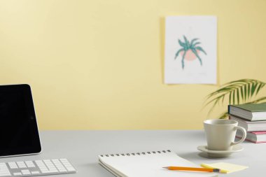 Ofis duvarının yanındaki masada dizüstü bilgisayarı, kaktüsü, defteri ve fincanı olan bir iş yeri.