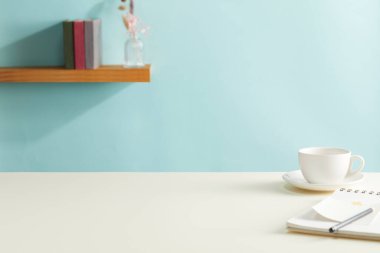 Boş beyaz kağıt bardaklı modern ofis masası, mavi arka planda kahve ve kırtasiye malzemesi. Metin için boşluk.