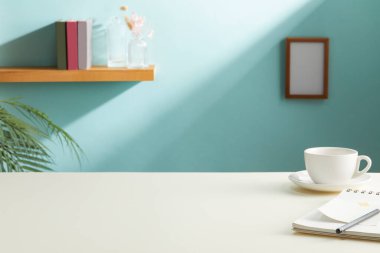 Oturma odasındaki masada defter ve kalemle kahve fincanı.