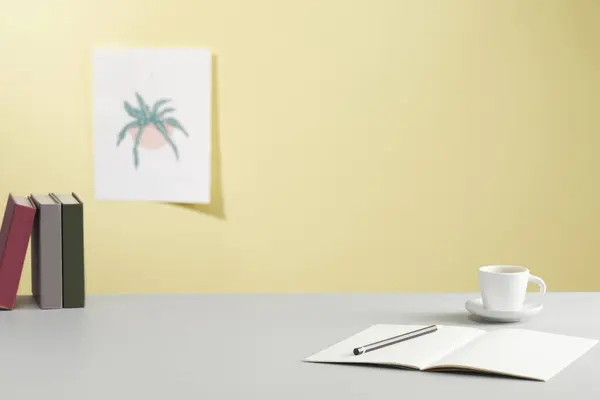 Modern bir çalışma alanının beyaz bir masa üzerinde bir kitap ve bitki içeren görüntüsü.