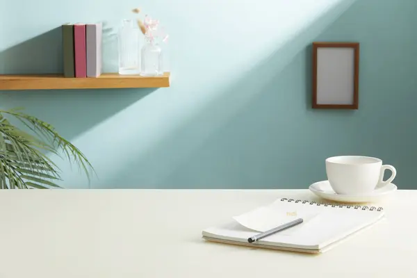 Boş defter, kupa ve bitki dolu modern işyeri.