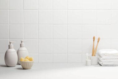 Beyaz seramik fayanslar, havlular ve arka planda banyo aksesuarları olan modern banyo iç mimarisi..