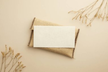 Bej arka planda boş kart ve pamuk çiçekleri. düz yatış, kopyalama alanı olan üst görünüm.