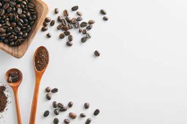 Kahve çekirdekli bir fincan sıcak içecek ve beyaz arka planda kaşık.