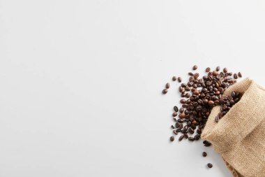 Beyaz arka planda kavrulmuş kahve çekirdekleri ve baharatlar.