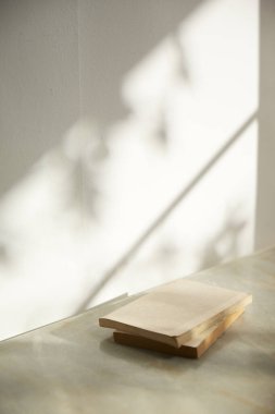 Ilık güneş ışığı, çimen yapraklarından gölgeler, masa üstünde vazo ve fincanlar gibi çeşitli nesnelerin olduğu bir oda.