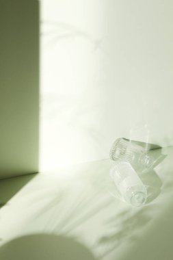 Ilık güneş ışığı, çimen yapraklarından gölgeler, masa üstünde vazo ve fincanlar gibi çeşitli nesnelerin olduğu bir oda.