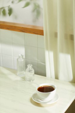 Sıcak bir öğleden sonra güneşinin, ağaç yaprakları manzaralı pencereden içeri girdiği rahat bir oda..