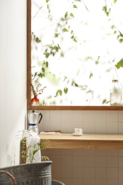 Sıcak bir öğleden sonra güneşinin, ağaç yaprakları manzaralı pencereden içeri girdiği rahat bir oda..