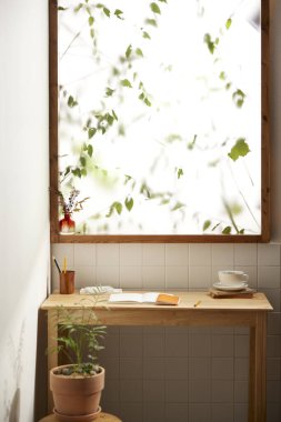 Sıcak bir öğleden sonra güneşinin, ağaç yaprakları manzaralı pencereden içeri girdiği rahat bir oda..