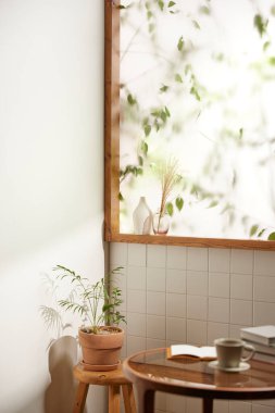 Sıcak bir öğleden sonra güneşinin, ağaç yaprakları manzaralı pencereden içeri girdiği rahat bir oda..