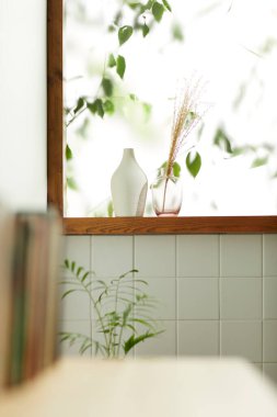 Sıcak bir öğleden sonra güneşinin, ağaç yaprakları manzaralı pencereden içeri girdiği rahat bir oda..