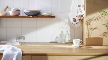 Beyaz fayans duvarlı güneşli bir mutfak, ahşap bir masa ve lavabo..