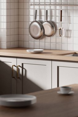 Parlak bej renkli bir mutfak. Pencereden içeri güneş ışığı giriyor..