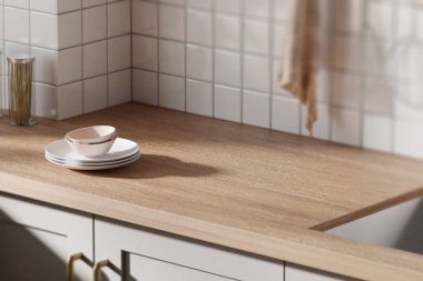 Parlak bej renkli bir mutfak. Pencereden içeri güneş ışığı giriyor..