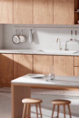 Parlak bej renkli bir mutfak. Pencereden içeri güneş ışığı giriyor..