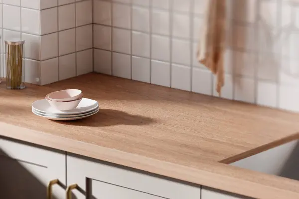 Parlak bej renkli bir mutfak. Pencereden içeri güneş ışığı giriyor..