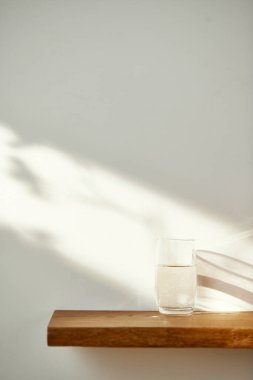 Bir su bardağı ve güneş ışığında bir masanın üzerindeki gölge..