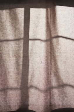 Arka planda gölgeler parlıyor. Pencereden içeri güneş ışığı giriyor..