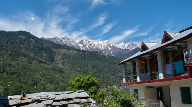 Gökyüzü, bulutlar ve karlı dağlarla dolu engin bir arazi..