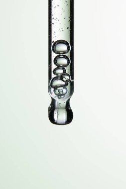 Kozmetik ve tıbbi görüntüler için kullanılabilen bir damlacıktan dökülen temiz sıvı damlacıklar.