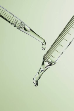 Kozmetik ve tıbbi görüntüler için kullanılabilen bir damlacıktan dökülen temiz sıvı damlacıklar.