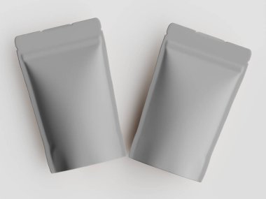 İki açık gri, düz kese beyaz bir yüzeye yerleştirilmiştir. Kese, muhtemelen kahve ya da benzeri ürünler için bir gıda paketleme tasarımı gibi görünüyor. Modern, minimalist bir tasarıma sahipler. Işık iyi aydınlatılmış bir ev ortamını işaret ediyor. Bu resim