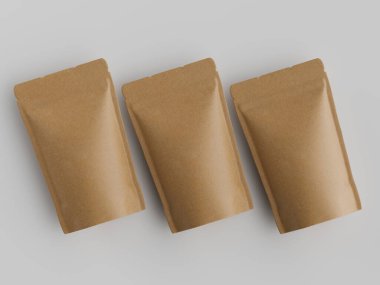 Açık gri arka planda yatay hizaya dizilmiş üç açık kahverengi kahve kesesi. Keseler dikdörtgen şeklinde ve pürüzsüz bir yüzeye sahipler. Aydınlatma bile parlak ve genel olarak ürünün net bir görüntüsünü oluşturuyor..