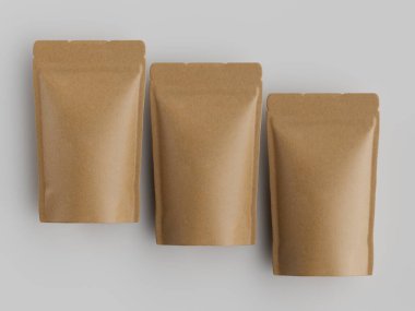 Tarafsız bir arkaplanda yatay sıraya dizilmiş üç açık kahverengi kağıt kesesi. Çantalar boş görünüyor ve gösterim amaçlı yerleştirilmiş. Işıklandırma eşit ve nötr, keselerin dokusunu vurguluyor. Resim c