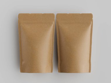 Açık gri bir yüzey üzerinde iki açık kahverengi kahve kesesi sergilenir. Kese düz ve pürüzsüz, mat bir finişe sahip. Tepedeki ışık gölge yaratmaz. Görüntü ambalaj tasarımı, markalaşma ve reklam için uygundur.