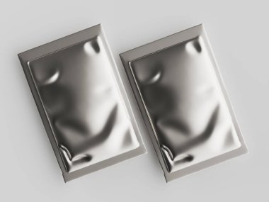 İki gümüş folyo kesesi açık gri bir yüzeyde sergileniyor, yukarıdan aşağıya doğru. Kesesinin buruşuk ya da buruşuk bir dokusu var. Metalik bir görünüm sergiliyor. Stüdyo ışıklandırması, paketleri sergilemek için uygun, temiz ve modern bir sunum öneriyor